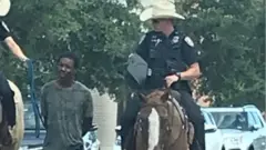 నల్లజాతి వ్యక్తిని తాడుతో చేతులు వెనక్కి కట్టేసి నడిపించుకుంటూ తీసుకెళ్తున్న ఫొటో