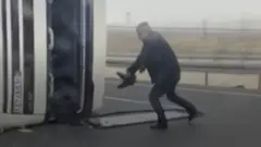 мужчина рядом с перевернутым грузовиком