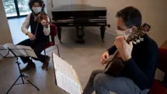 two men perform a violin and guitar