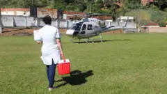 Profissional carrega órgão para transplante em caixa térmica em direção a helicóptero