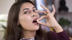 టాబ్లెట్ వేసుకుంటున్న భారతీయ మహిళ