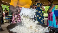 Du riz jeté dans un pot par une femme à Ganta, au Libéria