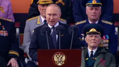 Vladimir Putin fala em púlpito com militares ao fundo