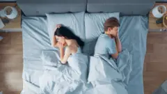 casal na cama, cada um virado para um lado