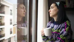Woman looking out of window (file image)
