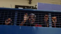 পুলিশের প্রিজন ভ্যানের ভেতর একজন দাঁড়িয়ে আছেন