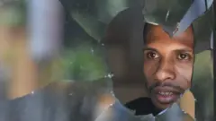 Warga melihat di balik kaca jendela yang pecah di Jayapura