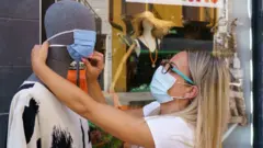 Une femme pose un masque sur un mannequin devant un magasin de vêtements à Aranda de Duero, près de Burgos, le 7 août