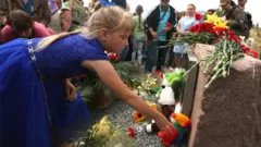 People lay flowers at the monument to the victims of the Malaysia Airlines flight MH17 crash, in the village of Grabovo, Ukraine, 17 July 2017