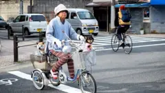 Lady riding bicycle with her pets
