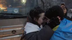 26-річна Ольга Курк-Малаєва обіймає свого 32-річного чоловіка Руслана, загорнутого в український національний прапор, звільненого військовополоненого, захопленого під час оборони Маріуполя у 2022 році, після його прибуття після обміну полоненими в Чернігівській області, у невідомому місці 5 лютого 2026 року, під час російського вторгнення в Україну. Україна та Росія провели свій перший обмін полоненими за кілька місяців.