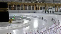 Worshippers dey perform Isha prayer as dem dey keep distance between dem next to di Kaaba for Mecca's Grand Mosque