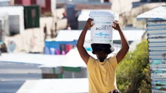 A woman carrying a bucket of fresh water to an informal settlement in Khayelitsha, near Cape Town- 31 March 2020