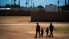 Duas mães caminham com seus filhos no Centro Residencial do Sul do Texas em 2019