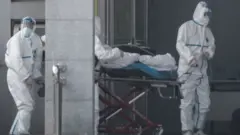 Medical staff carry a patient into the Jinyintan hospital in Wuhan on 18 January 2020.