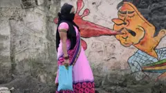 রাস্তায় ঘাটে থুতু ফেলার ঝুঁকি সম্পর্কে জনসাধরণকে সচেতন করার জন্য মুম্বাইয়ের একটি দেয়াল চিত্রের পাশ দিয়ে হেঁটে যাচ্ছেন এক নারী