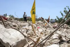 Una bandera amarilla de Hezbolá se erige de los escombros de lo que pudo ser un edificio.