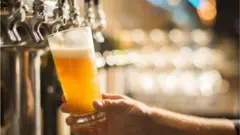 Copo de chopp sendo servido numa torneira