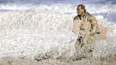A rescue worker stands in rough waters during the resumed search for missing water sports participants in The North Sea at Scheveningen