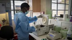 Umukozi wo mu kigo Rwanda Biomedical Centre arimo arapima Covid-19