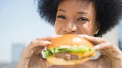 Une femme mangeant un hamburger.