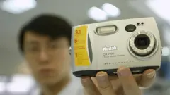 Um vendedor segura uma câmera digital da Kodak em uma grande loja de departamentos em Pequim