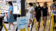 Placa pede atenção à distância recomendada entre as pessoas em um shopping