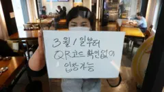 28일 서울의 한 식당 입구에 식당 관계자가 오는 3월 1일부터 시행되는 방역패스 적용 일시 중단 관련 안내문을 부착하고 있다