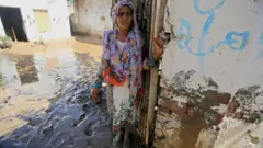 A woman stands outside her house in the aftermath of floods in Charsadda District, Khyber Pakhtunkhwa province, Pakistan, 28 August 2022.