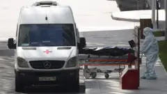 Тело умершего погружают в машинй скорой помощи