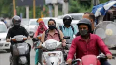 Commuters on motorcycles wear face masks after new stricter guidelines in wake of the Covid19 outbreak, in Amritsar, India, 21 August 2020