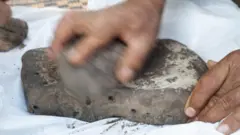 Hombre moliendo granos sobre una piedra
