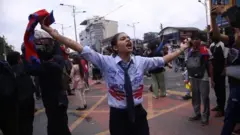 La jeune femme exposée en haut de l'article s'est ouvert les bras le 8 septembre 2025, tenant le drapeau du Népal avec son bras droit et a crié des slogans. Elle se tenait au milieu d'un croquet marqué jaune, avec des gens qui se tenaient autour d'elle.