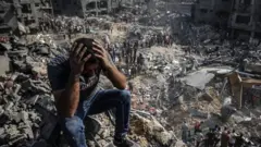 A man, sitting on debris, clutches his head as Palestinians conduct a search and rescue operation after the second bombardment of the Israeli army in the last 24 hours at Jabalia refugee camp in Gaza City, on 1 November 2023