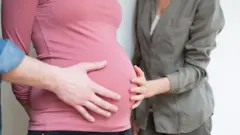 Um casal toca a barriga de uma mulher grávida