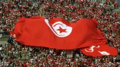 جماهير تونس ترفع علماً وطنياً ضخماً، خلال مباراة فريقها ضد فريق إنجلترا في كأس العالم 1998