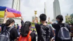 กลุ่มเด็กมัธยมยืนชูสามนิ้วที่อนุสาวรีย์ประชาธิปไตย