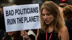 A la COP 25, une militante de la protection de l'environnement tient une pancarte accusant de "mauvais politiciens" de détruire la planète.