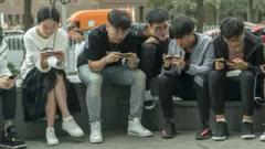 天津一群年輕人坐在購物商場外打手機連線遊戲（資料圖片）