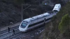 Des membres de la Garde civile espagnole devant un train blanc déraillé participent aux opérations de sauvetage.