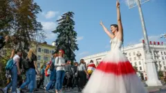 زن معتزض با پوشیدن لباس سفید و قرمز در تظاهرات ضد دولتی