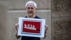 Hong Kong cartoonist Wong Kei-kwan or Zunzi holds up one of his works that said "press freedom"