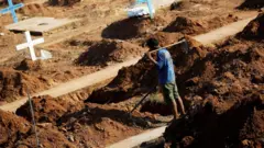 A worker prepares graves at the Sao Sebastiao cemetery in Altamira, Brazil