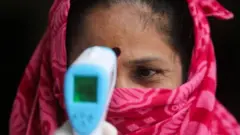 An Indian women has her temperature checked
