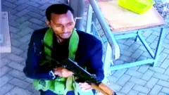 A gunman is pictured as he and others make their way into a hotel and office complex in Nairobi, Kenya, 15 January 2019