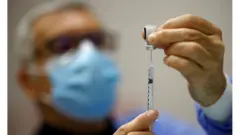 Homem enche seringa com vacina da Pfizer contra covid-19