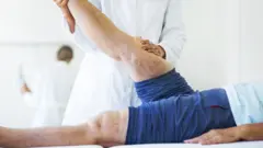 Profissional da saúde analisa pernas de pessoa com varizes