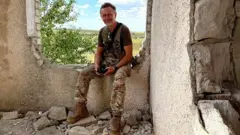 El partisano Serhii sentado en un edificio en ruinas
