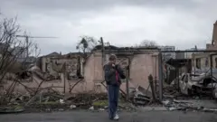 Mwanamke akikagua uharibifu eneo la Bucha karibu na Kyiv