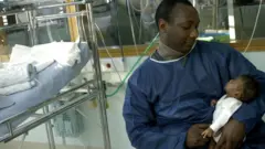 Papa and im ew born pikin inside hospital.